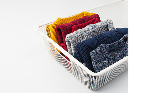 Basket with different coloured jumpers folded inside