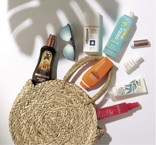 Flat lay of a round woven bag and sun tanning products