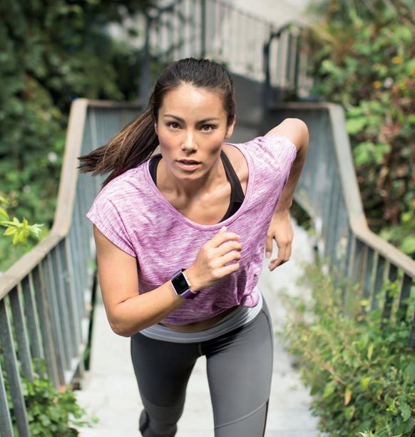 Athletic woman running outdoors wearing a smartwatch